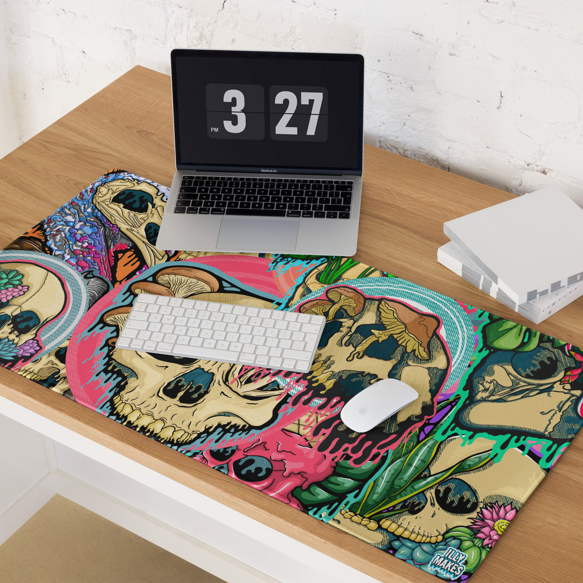 Product mockup of Illymakes gaming mousepad with a colorful collage of dripping skulls, mushrooms, and florals, shown with a keyboard, mouse, and headphones.